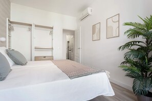 A bedroom with a bed, a wardrobe, a mirror, a potted plant, and two wall art pieces. - Genteel Home Reina Sof a IV (Madrid)