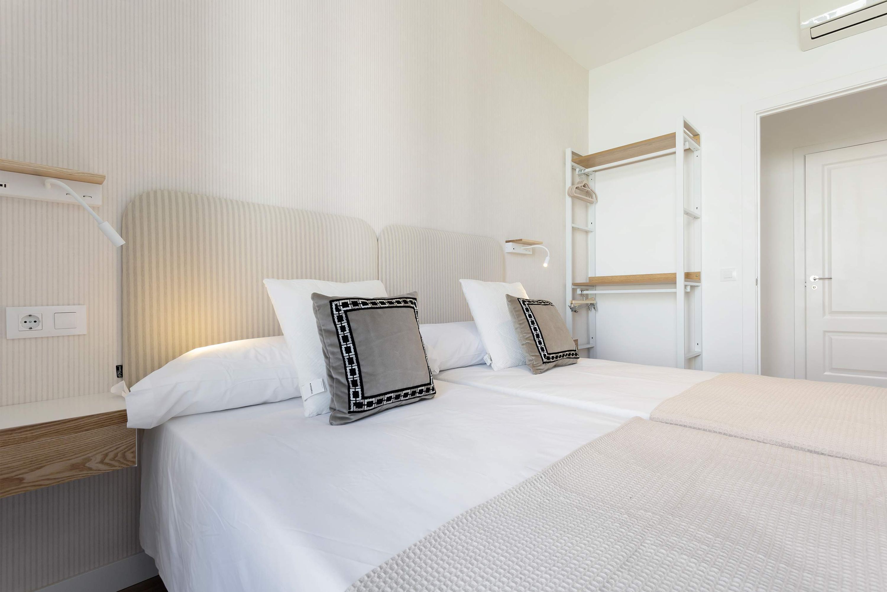 Ett hotellrum med en säng, sängbord, en spegel och en garderob.