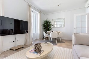A modern living room with a flat-screen TV, a dining area with a table and chairs, and a large mirror on the wall. - Genteel Home Reina Sof a IV (Madrid)