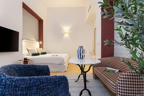 A modern hotel room with a bed, a sofa, a small table, and a TV. - Genteel Home Padre Marchena 13 002 (Seville)