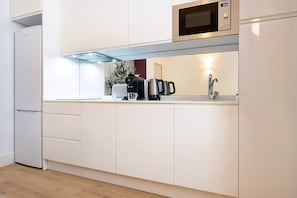 Eine moderne Küche mit integriertem Mikrowellenherd, einer Kaffeemaschine und einem Wasserkocher.