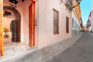 Eine Straße mit Gebäuden im traditionellen Baustil, einem Metallgitter und einem Blumentopf.