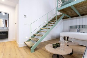 Ein modernes Interieur mit Treppe, einer Couch und einem runden Tisch mit Kerzen und einem Glas.
