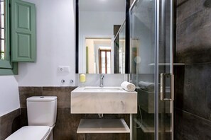 Ein modernes Badezimmer mit einer Duschkabine aus Glas, einer weißen Toilette und einem Marmorwaschbecken.