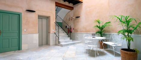 Un patio con una puerta verde, una escalera y mobiliario exterior con plantas en macetas.