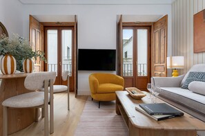 A living room with a sofa, armchairs, a coffee table, a TV, and a bookshelf. - Genteel Home Padre Marchena 13 202 (Seville)
