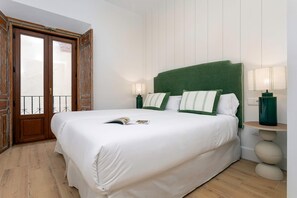 Ein ordentlich bezogenes Bett mit weißen Bettwäsche, einem grünen Kopfteil und zwei Nachttischlampen.