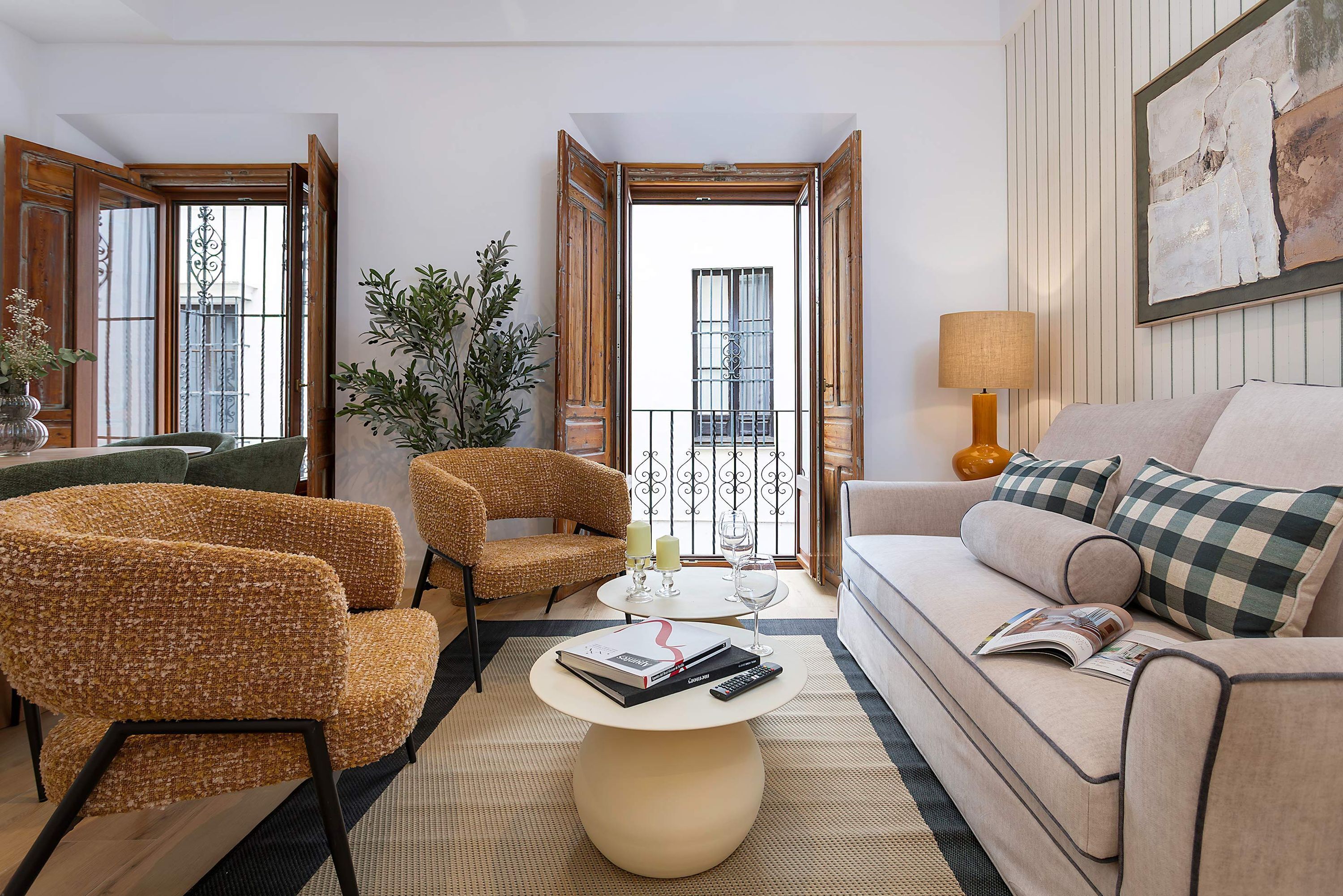 A living room with a sofa, two armchairs, a coffee table, and a balcony with a view.