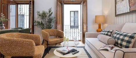 Een woonkamer met een bank, twee fauteuils, een salontafel en een balkon met uitzicht.