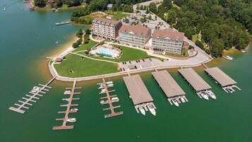 An aerial view of a hotel with a large building, a swimming pool, and a marina with boats.