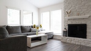 Una sala moderna con un sofá gris, una mesita de centro blanca y una chimenea de piedra.