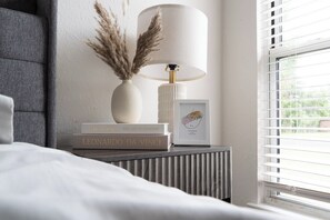 A neatly arranged bedside table with a lamp, a framed photo, and books.