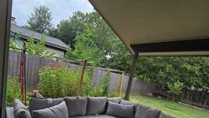 Un espacio de estar al aire libre cubierto con un sofá modular y una mesa de centro de vidrio.
