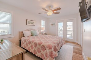 Ein Schlafzimmer mit einem Bett, einem Deckenventilator, einem Fernseher und einem Balkon.