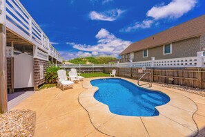 A backyard with a swimming pool, lounge chairs, and a wooden fence. - JL #472 On the Rocks - Oceanfront - Pool - Hot tub (Nags Head)