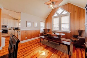A spacious kitchen with wooden cabinets, a dining area with a table and chairs, and a ceiling fan. - JL #472 On the Rocks - Oceanfront - Pool - Hot tub (Nags Head)