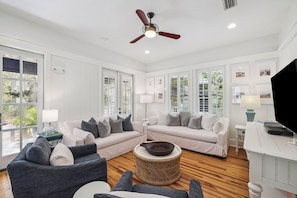A spacious living room with a ceiling fan, white walls, and large windows. - 2 Blocks to Beach | Screened-in Porch (Santa Rosa Beach)