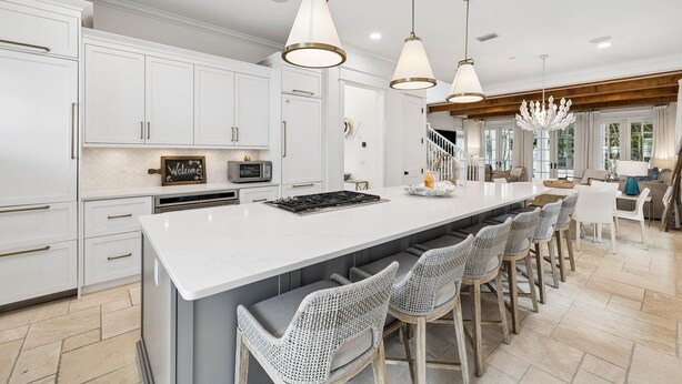 A spacious kitchen with white cabinetry, a central island with bar stools, and pendant lighting. - Walk to Beach and Square | Private Pool (Inlet Beach)