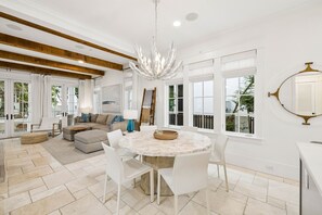 A modern kitchen with a round marble table, white chairs, and a chandelier. - Walk to Beach and Square | Private Pool (Inlet Beach)