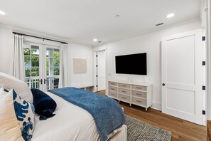 A bedroom with a bed, a dresser, a television, and a door. - Walk to Beach and Square | Private Pool (Inlet Beach)