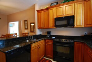 A kitchen with wooden cabinets, a microwave, a stove, and a sink. - Roomy 4BR Beach Home for 10 | Walk to Ocean (Myrtle Beach)