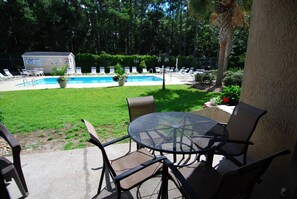 Un patio trasero con piscina, sillas de descanso y una mesa.