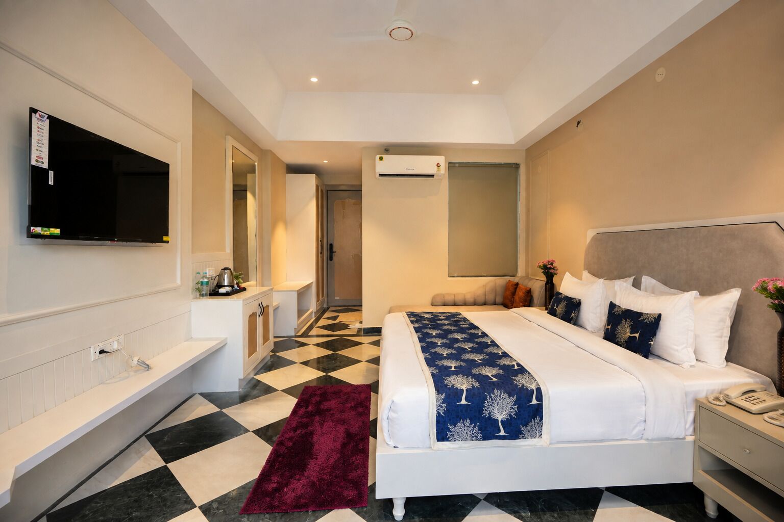 Ein Hotelzimmer mit Bett, Fernseher, Bad und einer Rezeption.