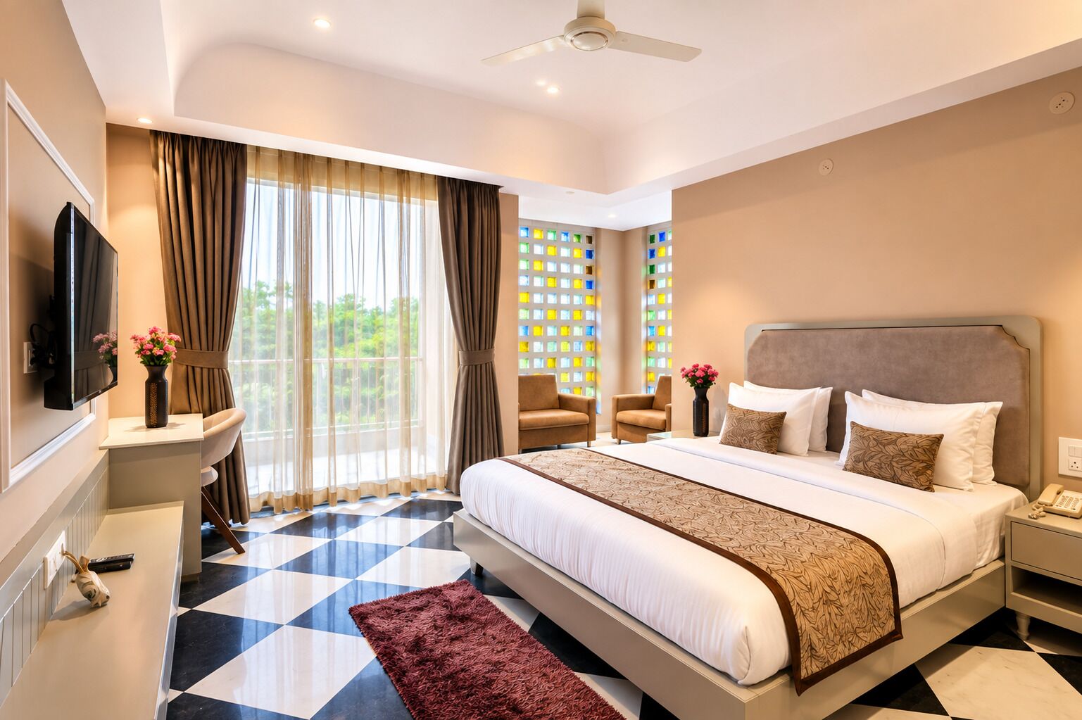 Habitación de hotel con una cama grande, televisión, escritorio con un florero y vista a zonas verdes por la ventana.