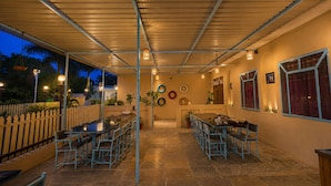An outdoor patio area with tables and chairs, a fence, and a wall with decorative plates. - The HariMahal -A Luxury Hotel in Udaipur (Udaipur)