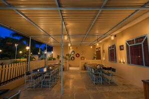 An outdoor patio area with tables and chairs, a fence, and a wall with decorative plates. - The HariMahal -A Luxury Hotel in Udaipur (Udaipur)
