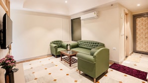 A living room with a green sofa, a coffee table, and a flat-screen TV. - The HariMahal -A Luxury Hotel in Udaipur (Udaipur)