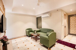 A living room with a green sofa, a coffee table, and a flat-screen TV. - The HariMahal -A Luxury Hotel in Udaipur (Udaipur)