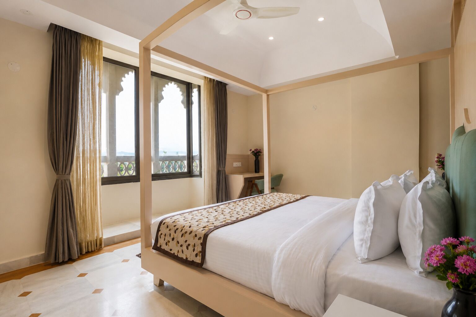 Ein modernes Schlafzimmer mit einem Himmelbett, einem Schreibtisch und Blick ins Freie.