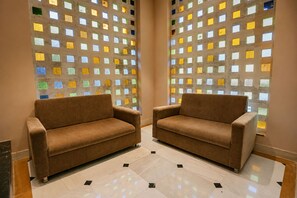 Two brown sofas in a room with a tiled floor and a wall with colorful square patterns. - The HariMahal -A Luxury Hotel in Udaipur (Udaipur)