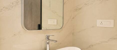 A bathroom with a white vessel sink, a mirror, and a wooden vanity.