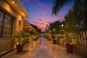 A corridor with potted plants, a building with a dome, and a sunset sky. - The HariMahal -A Luxury Hotel in Udaipur (Udaipur)