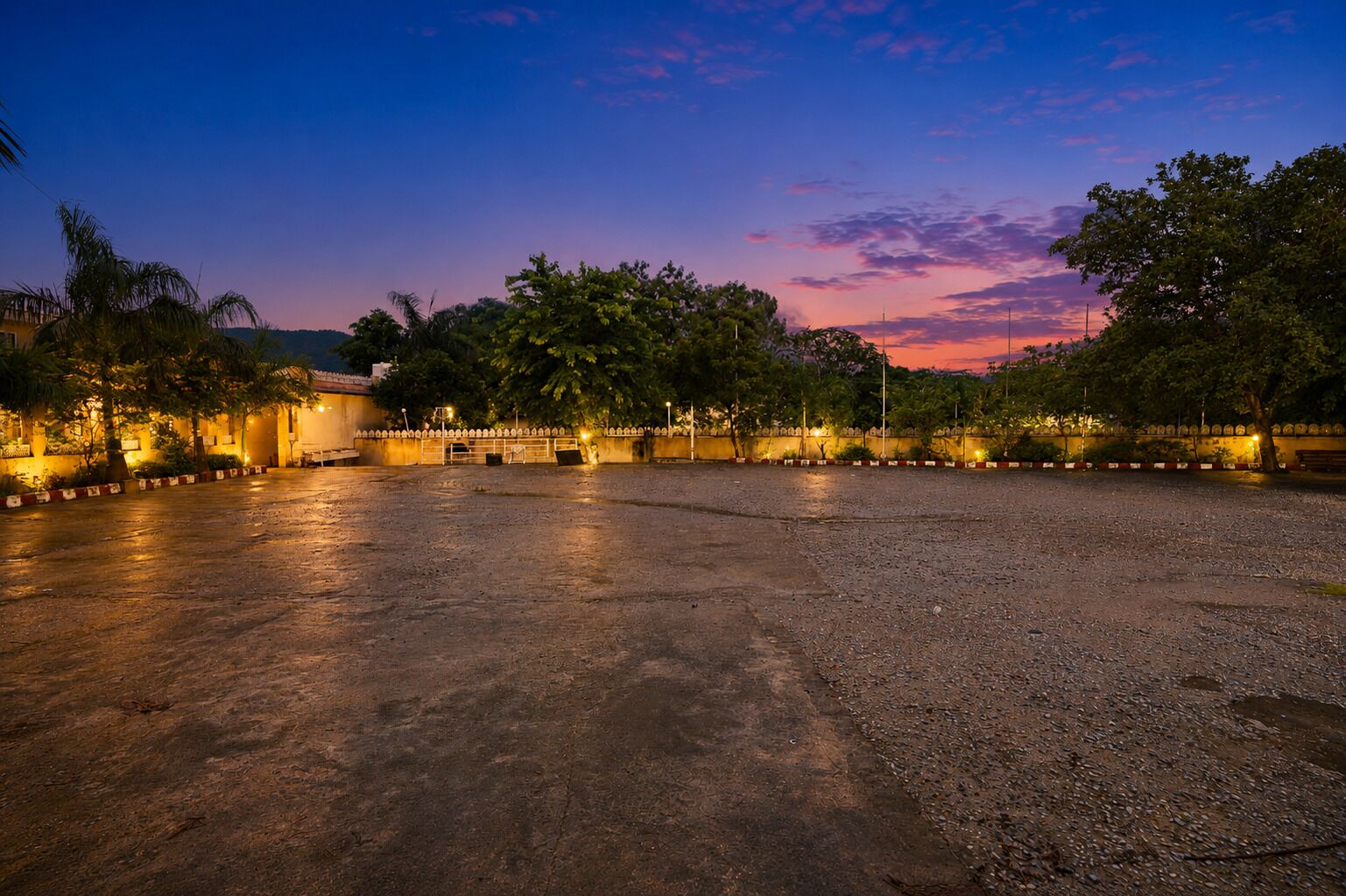 An open paved area with trees and a building in the background.