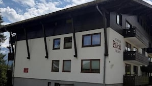 Un edificio de dos pisos con techo plano y un balcón en el nivel superior.