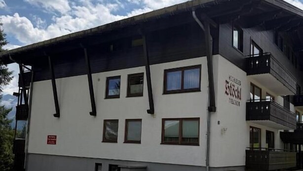 Ein zweistöckiges Gebäude mit Flachdach und einem Balkon im oberen Geschoss.