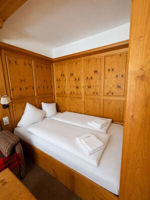 A double bed with white linens, a wooden headboard, and a bedside table with a lamp. - Haus Stöckl Top 14 (Königsleiten)