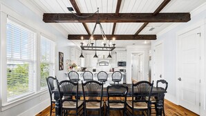 A dining room with a wooden table and chairs, white walls, and a ceiling with exposed beams. - Marimac's Maison|Private Pool|Elevator|Golf Cart (Inlet Beach)