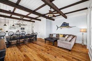 A spacious living area with a wooden floor, a dining table with chairs, a sofa, and a ceiling fan. - Marimac's Maison|Private Pool|Elevator|Golf Cart (Inlet Beach)