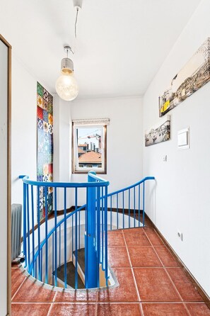 Eine Wendeltreppe mit blauen Geländern, die zu einer oberen Etage führt.
