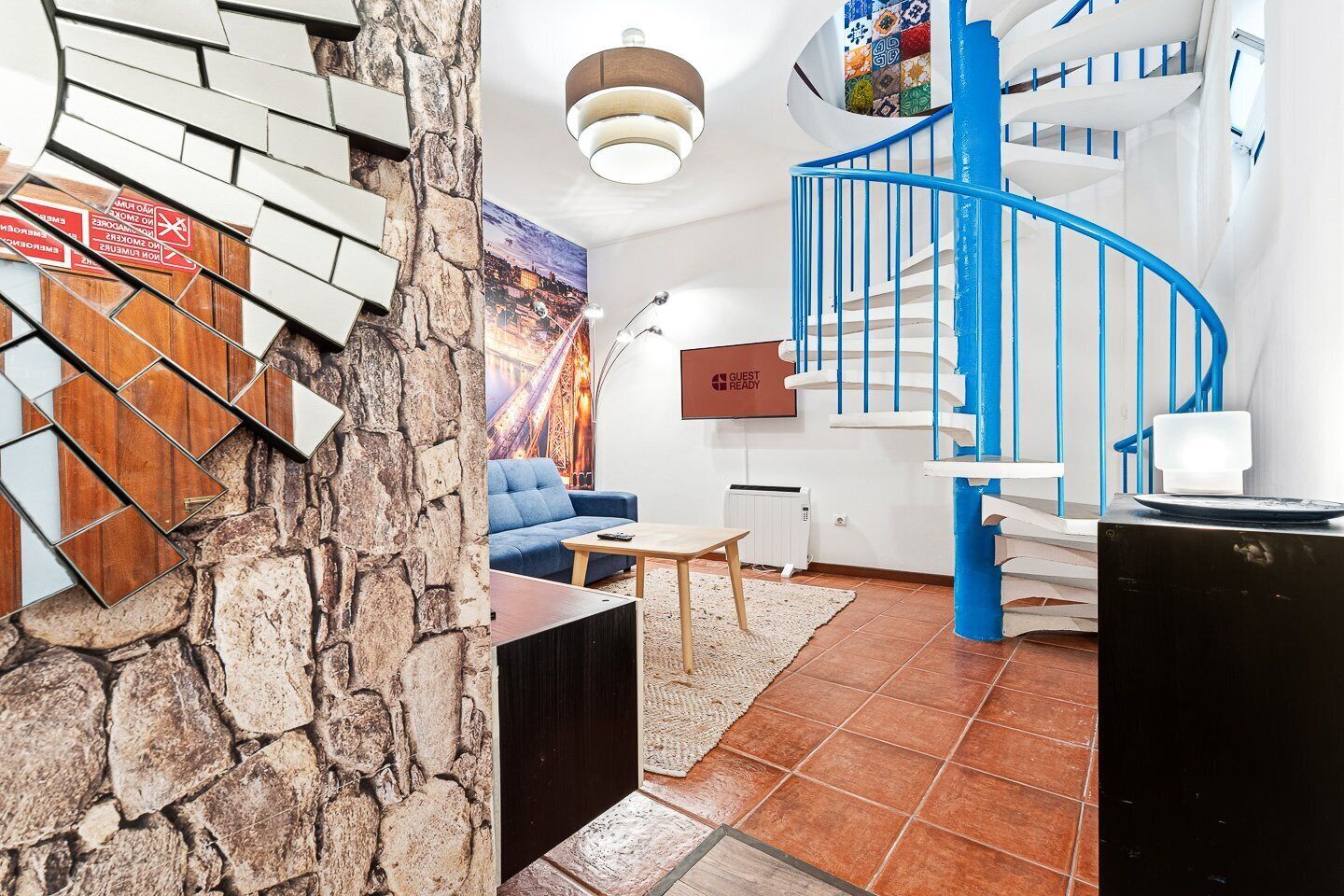 Una sala de estar moderna con un sofá azul, una mesa de centro y una pared de piedra.