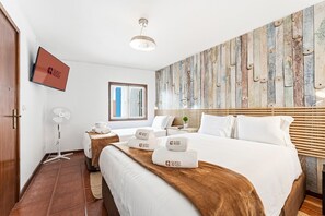 Ein Hotelzimmer mit einem Bett, einem Nachttisch, einem Flachbildfernseher, einem Wandbild und einem Fenster.