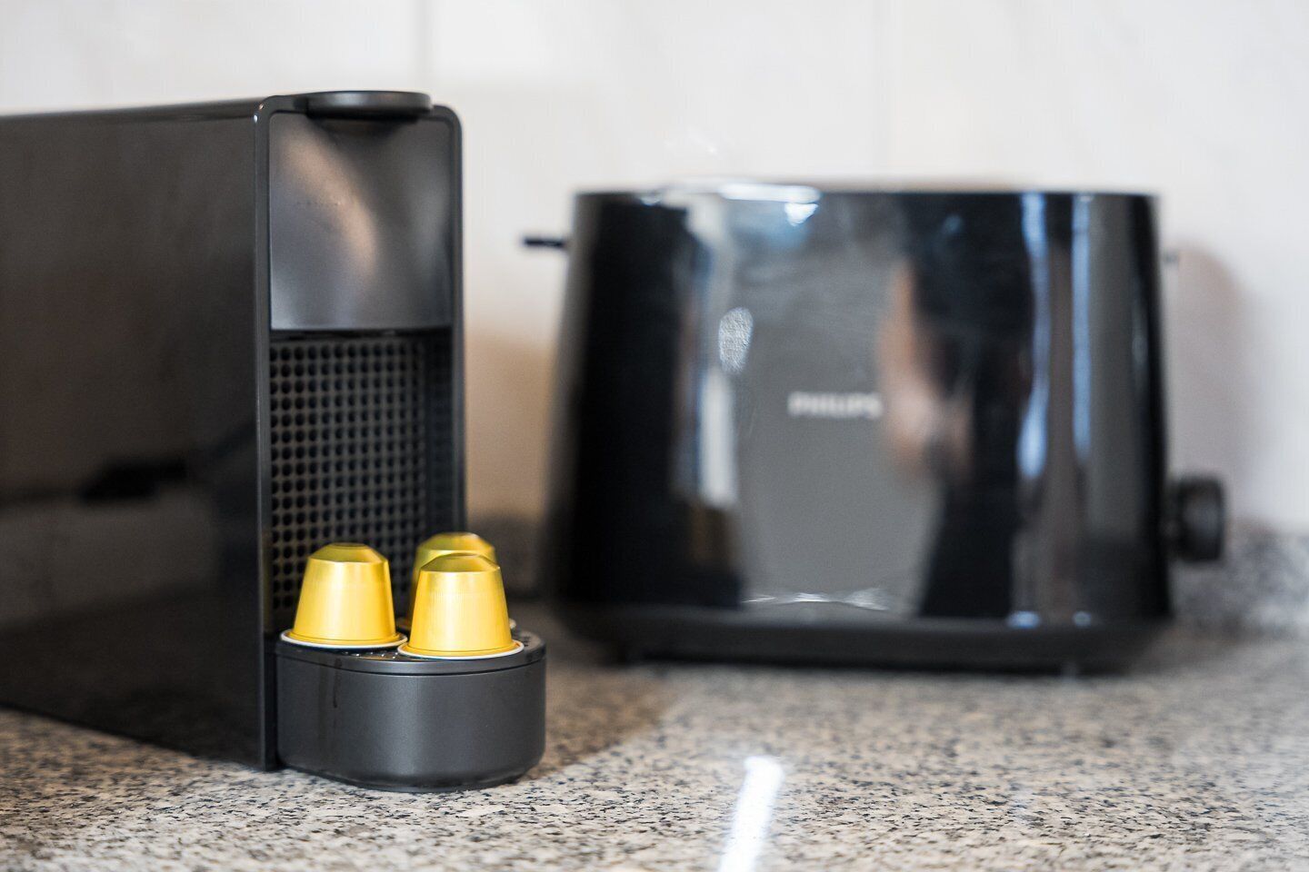 A kitchen with a coffee maker and a black appliance, possibly a rice cooker, on a granite countertop.