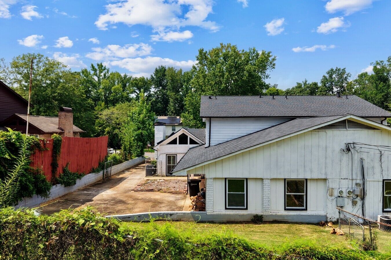 A residential area with a house featuring a sloped roof, a front yard with a pathway, and a red fence.