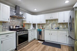 A modern kitchen with white cabinets, stainless steel appliances, and a patterned backsplash. - Hoover Furnished Stay | Families & Pros (Birmingham)