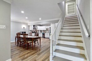 A spacious kitchen with wooden flooring, white cabinets, and a staircase leading to an upper level. - Hoover Furnished Stay | Families & Pros (Birmingham)