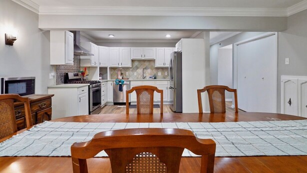 A spacious kitchen with white cabinets, a dining table with chairs, and a microwave. - Hoover Furnished Stay | Families & Pros (Birmingham)